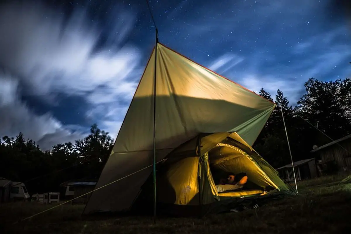 A person laying in air conditioned camping tent