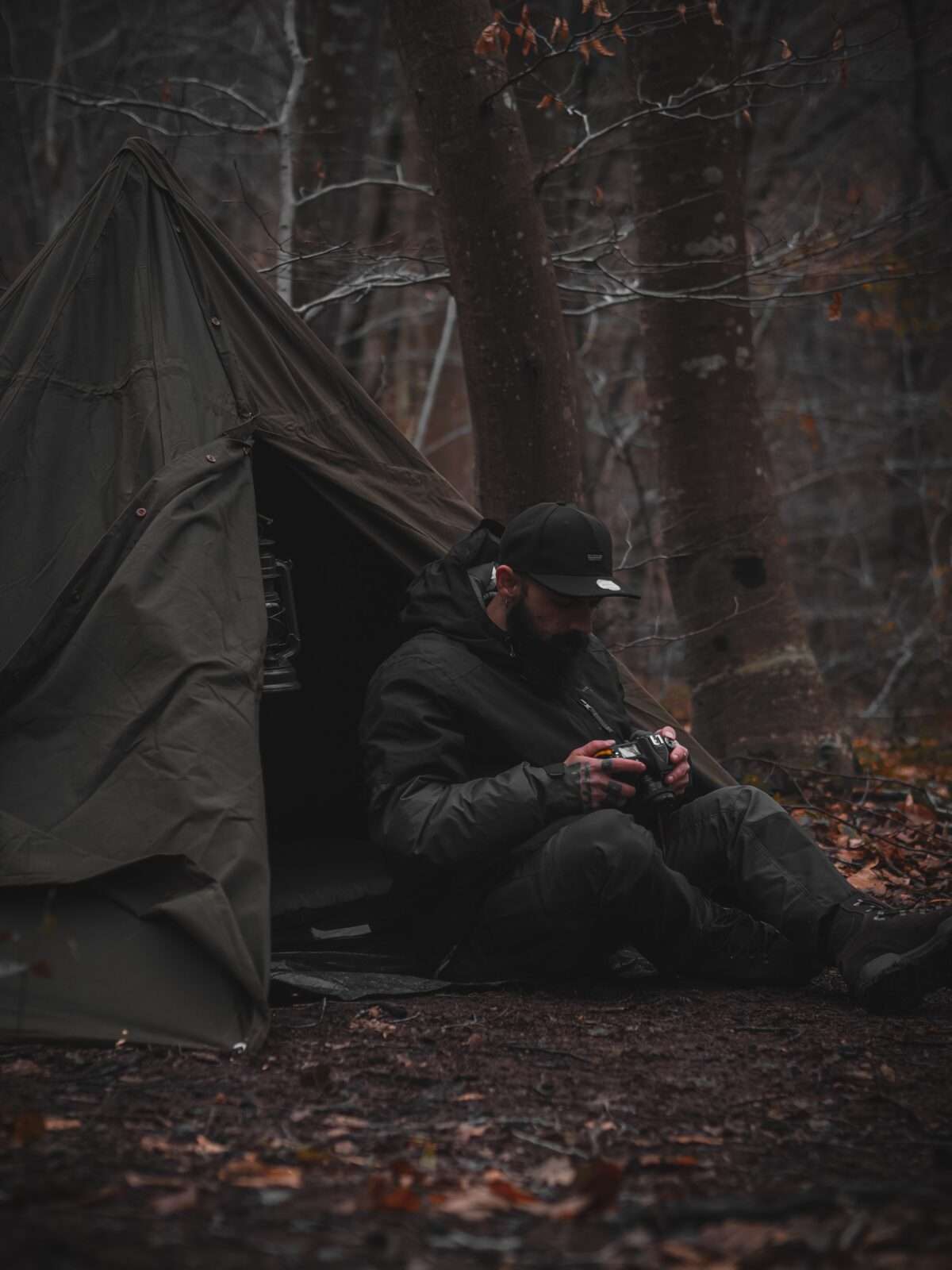 A man sitting in tent and looking in his camera for something