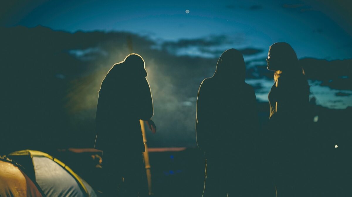 girls standing around their camp while camping