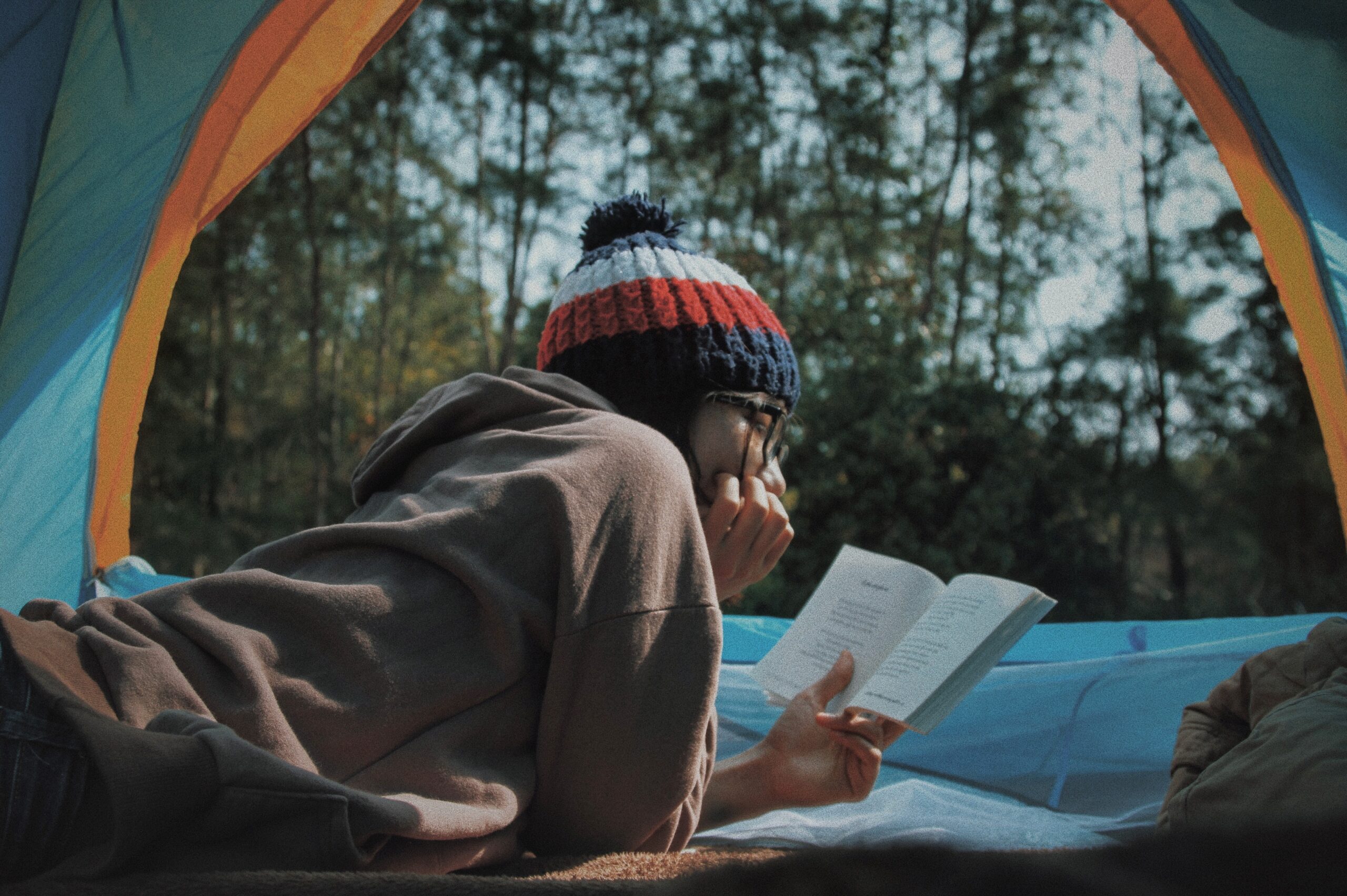 a girl lying in the tent reading her book