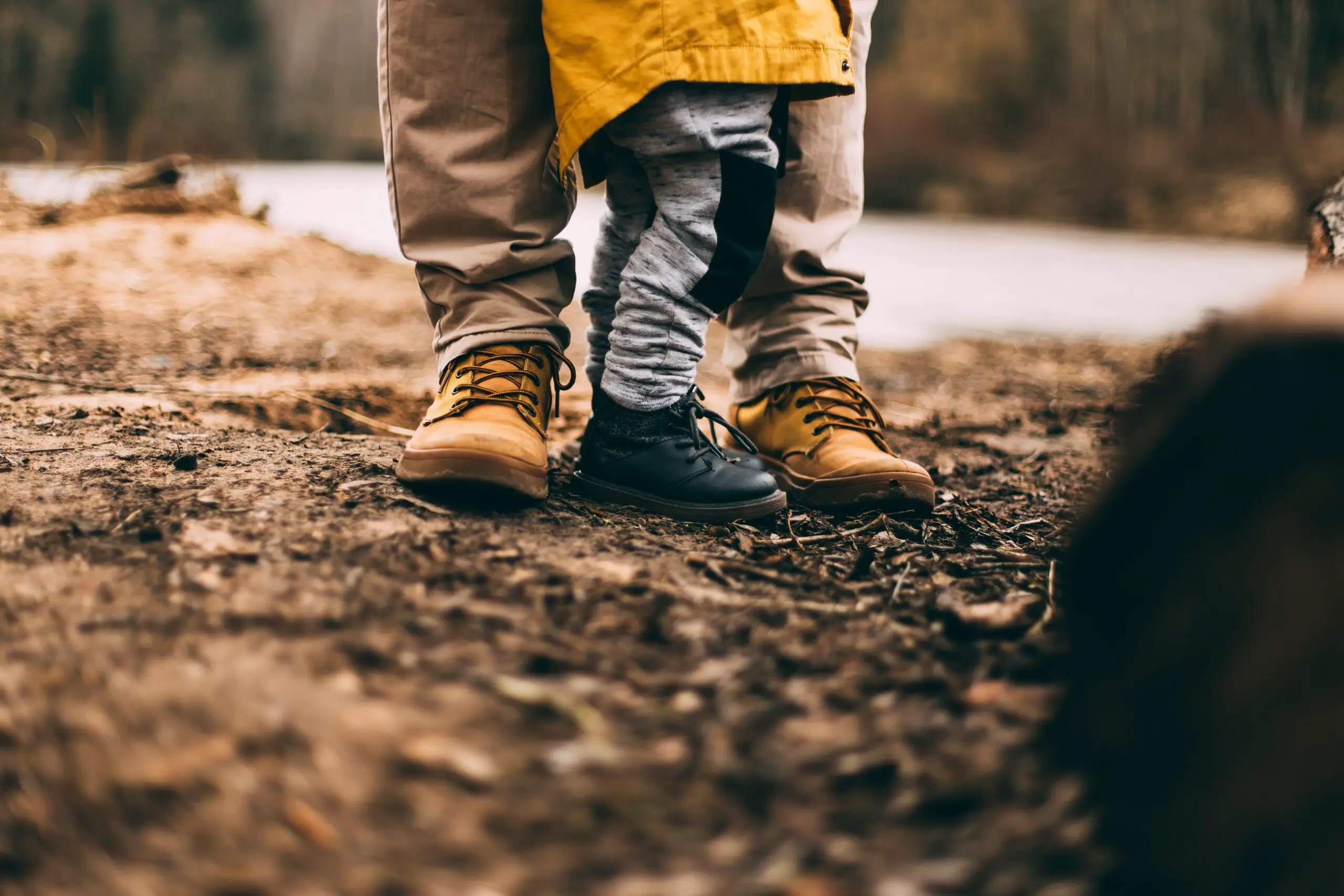 legs of baby and his father standing in the middle of the jungle while camping