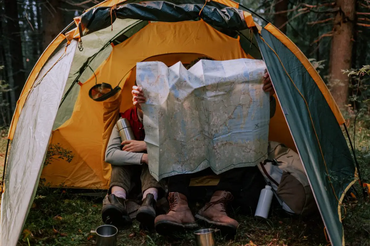 two person sitting in the tent camp reading the map