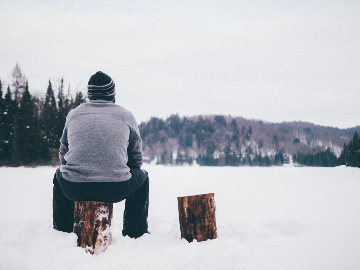 A men sitting on the piece of wood near his camp