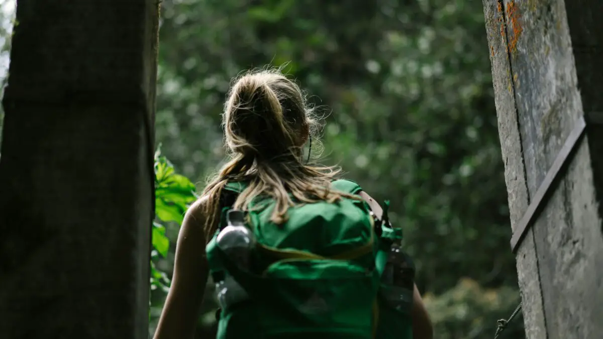The Girl with her camping backpack wandering in the jungle