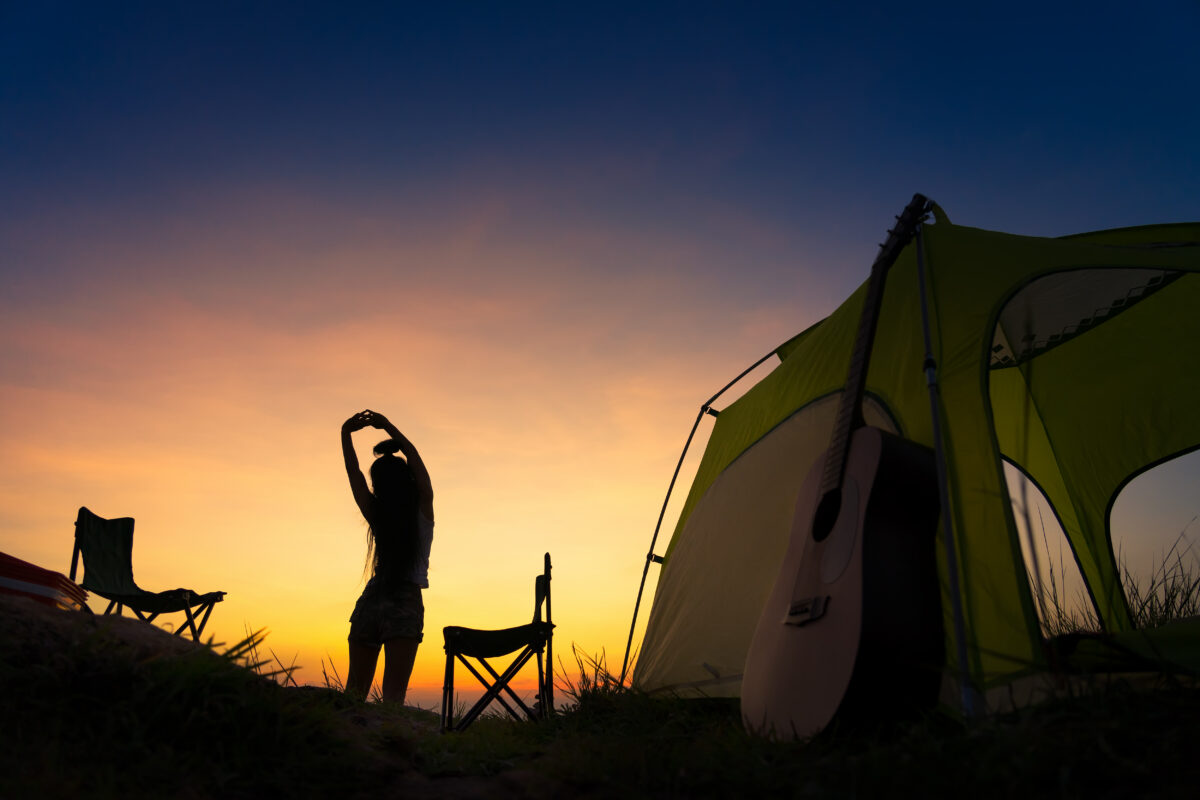 A girl standing near the camp in the sunset