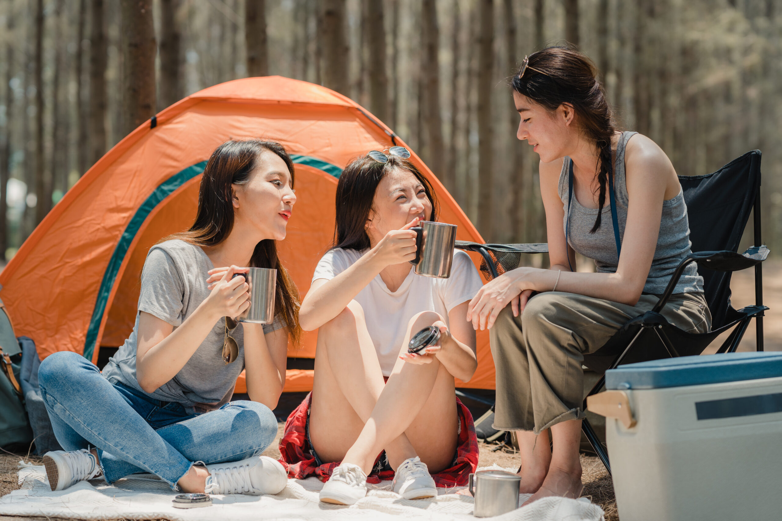 Three girls sitting near their camping tent discussing how to winterize a camper